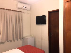 圣若昂达博阿维斯塔Hotel Giordano Centro的小房间设有一张床和墙上的电视