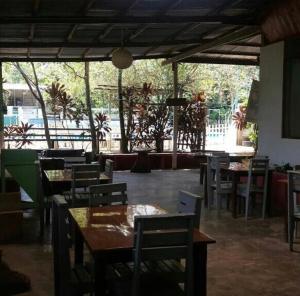 马尔多纳多港Villa Hermosa de Tambopata Casa Hospedaje & Hostel的餐厅设有木桌、椅子和大窗户。