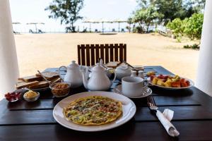 AmbalantotaLadja Beach Resort的海滩上一张桌子,上面放着一盘食物和茶