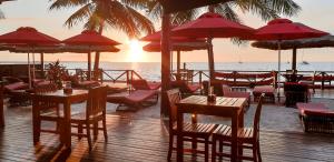 南迪斐济威洛艾洛海滩华美达酒店 的海滩上的餐厅,配有桌子和遮阳伞