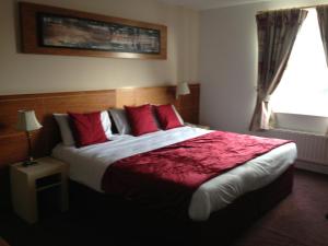 阿什本阿什伯恩酒店的一间卧室配有一张带红色枕头的大床和窗户