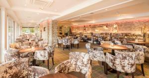 巴洛赫Duck Bay Hotel & Restaurant的一间在房间内配有桌椅的餐厅