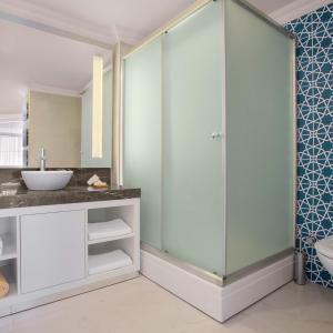 库萨达斯Paloma Marina Suites - Adult Only的一间带玻璃淋浴和水槽的浴室