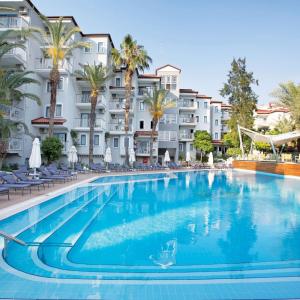 库萨达斯Paloma Marina Suites - Adult Only的一座棕榈树和建筑的大型游泳池