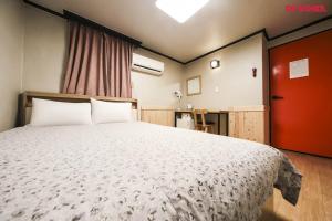 首尔仁寺洞R旅舍的一间卧室设有一张大床和一扇红色的门