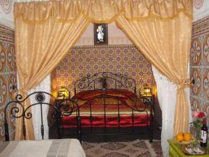 塔鲁丹特玛丽亚姆塔鲁丹特里亚德酒店的一间卧室配有一张带红色床罩和窗帘的床