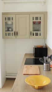 维希Appartement avec vue panoramique的厨房配有白色橱柜和柜台上的黄色盘子