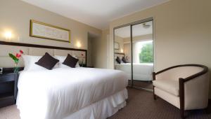 利马罗斯福套房酒店的卧室配有一张白色大床和一把椅子