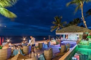 拉迈Samui Jasmine Resort - SHA Plus的一位晚上站在海滩酒吧前的人