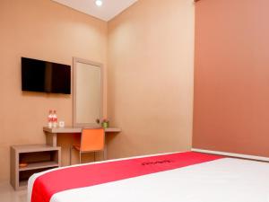 三宝垄RedDoorz near Java Supermall Semarang的一间卧室配有一张床和一张带镜子的书桌