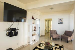 蒂蒂卡韦卡Mai'i Villa Apartment - 1的客厅配有电视、2把椅子和1张桌子