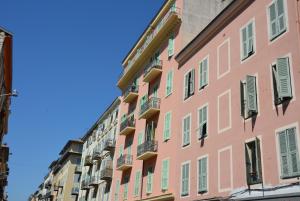 尼斯Be our Guests in Nice Port Bonaparte的粉红色建筑的外墙,有绿色百叶窗