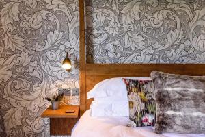 MauldenThe George Inn的一间卧室配有床和壁纸墙