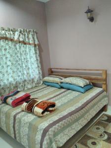 珍南海滩兰卡威普劳民宿的一间卧室配有带两个枕头的床和窗户