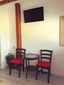 锡比乌Casa Simion的三把椅子和一张桌子,墙上有电视