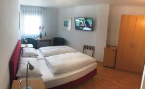 莱茵河畔的宾根幸福酒店的一间卧室设有两张床,墙上配有电视。