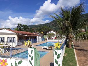 兰巴里Pousada São Pedro的一座带椅子的游泳池,一座棕榈树旁边