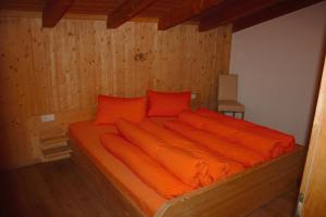 朗根费尔德阿尼塔公寓酒店的木质客房内的一张带橙色床单的床