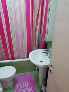 尼亚普拉莫斯HOLIDAYS HOUSE Νέα Πέραμος的一间带水槽、卫生间和粉红色淋浴帘的浴室
