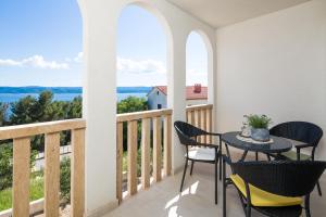 马鲁希奇Appartments Villa Daria的阳台配有桌椅,享有水景。