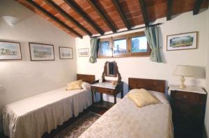 蒙特里久尼Monteriggioni Castello的一间卧室配有两张床和一张带镜子的桌子