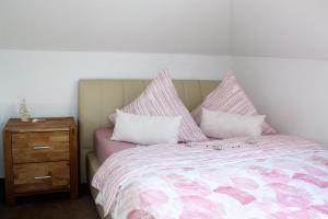 库克斯港Ferienwohnung Hermann-Daur-Weg的一张配有粉色和白色床单的床和木制床头柜