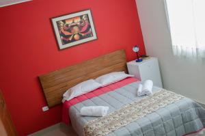 伊察Jazmines Lodging的一间卧室设有红色的墙壁和一张带毛巾的床