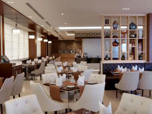 迪拜Two Seasons Hotel & Apartments的一间设有白色桌椅的餐厅和一间酒吧