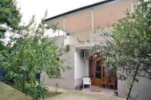 库塔伊西Center Villa Kutaisi的白色的房子,设有门廊和椅子,树木繁茂