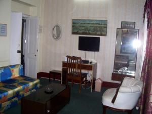 加尔各答蓝筹旅馆的客厅配有沙发、椅子和电视