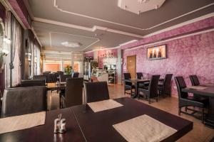 奥西耶克Domin Osijek的餐厅设有桌椅和粉红色的墙壁
