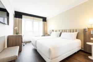 拉科鲁尼亚Eurostars Atlántico的酒店客房配有两张床和一张书桌