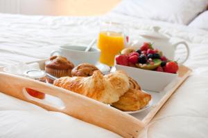 布拉格Seven Wishes Boutique Residence的床上的早餐托盘,包括糕点和水果