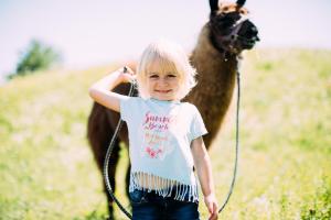 皮茨河谷阿兹尔Pitzis Kinderhotel - Family Only的一位年轻女孩在田野里骑骆驼