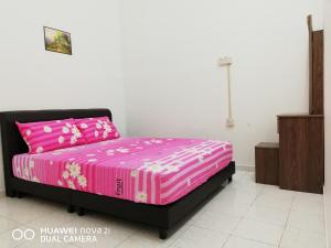 太平Taiping Guest House的一间卧室配有一张带粉色床单和粉色的床。