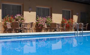 滨海托萨Hotel Mar de Tossa的一座带椅子和鲜花的游泳池,位于大楼旁