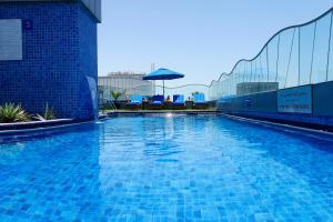 迪拜迪尔拉萨玛雅酒店的一个带椅子和遮阳伞的大型蓝色游泳池