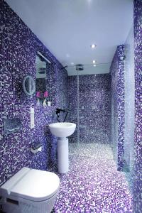 莱比锡阿比托套房酒店的浴室设有卫生间和紫色瓷砖淋浴。