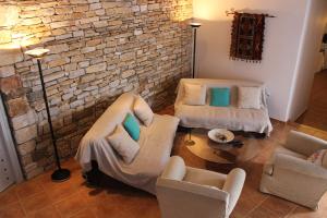KóstosGuesthouse Casa De La Roca , Kostos , Paros的客厅配有两把椅子和砖墙