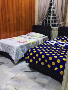 乔治市Bayan Baru Homestay @ Taman Sri Nibong的客房内的两张床和波卡圆顶床单