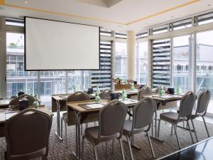 安曼阿尔占罗塔纳酒店的一间会议室,配有桌椅和大屏幕