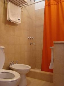 蒂尔卡拉Rinconcito en Tilcara的浴室设有橙色的淋浴帘和卫生间
