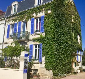 卢昂Gîte chez Madeleine的常春藤覆盖的房子,设有蓝色的窗户和蓝色的百叶窗