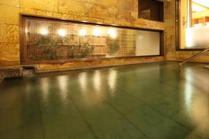 轻井泽鹤屋旅馆 的游泳池设有瓷砖地板和窗户