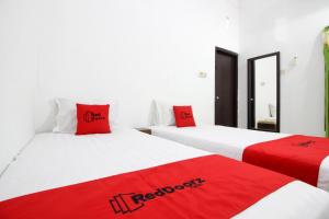 日惹阿迪素拓机场附近3号红门酒店的客房内的两张床和红色枕头