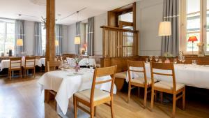 埃夫林根基兴瓦尔赛斯餐厅酒店的餐厅设有白色的桌椅和窗户。
