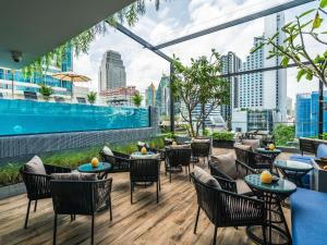曼谷Tastoria Collection Sukhumvit - SHA Extra Plus的一个带桌椅的屋顶露台和游泳池