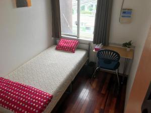 那霸久茂地旅馆的小房间设有一张床和一把椅子