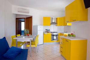 圣贝内代托-德尔特龙托Residence Acquamarina的厨房配有黄色橱柜和一张带黄色椅子的桌子