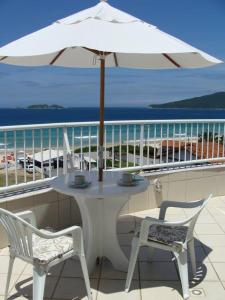 弗洛里亚诺波利斯Praia Pousada Tatuíra的阳台上配有带雨伞的白色桌子